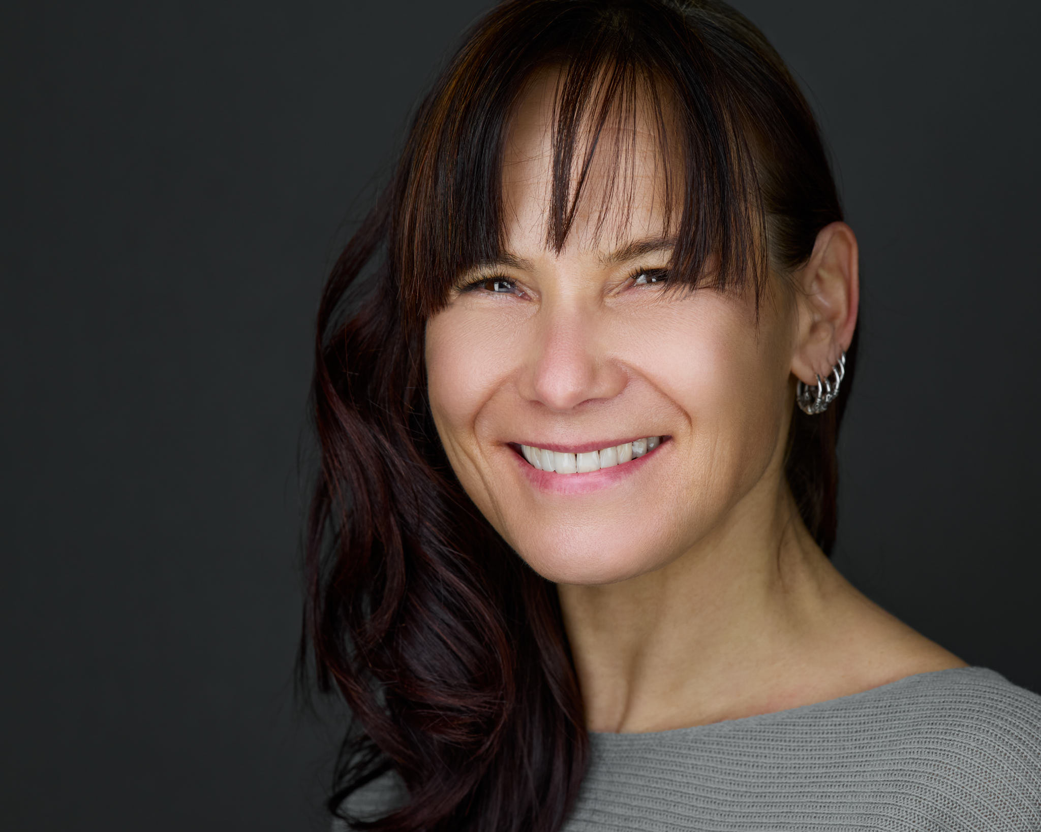 Personal-Branding-Portrait einer Frau mit dunklem Haar vor grauem Hintergrund, fotografiert von Christian Volk