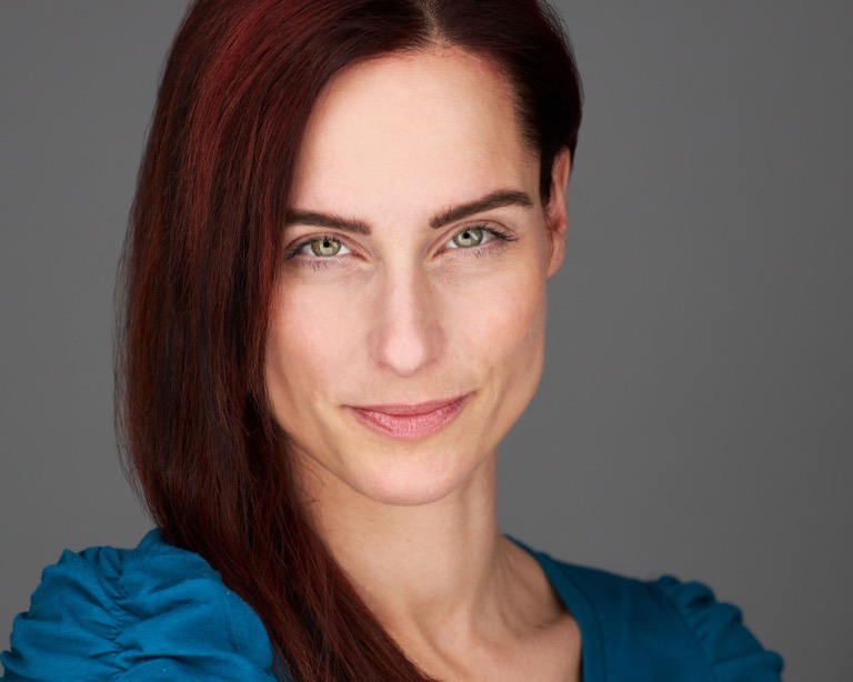 Schauspieler-Headshot einer Frau mit rotbraunem Haar vor grauem Hintergrund, fotografiert von Christian Volk