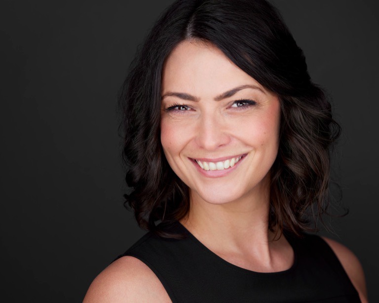 Schauspieler-Headshot einer Frau mit dunklen Locken vor dunklem Hintergrund, fotografiert von Christian Volk
